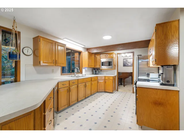 a open kitchen with stainless steel appliances granite countertop a refrigerator a sink a stove and oven with wooden floor