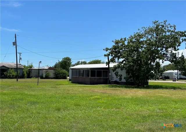 a view of a house with a big yard and palm trees