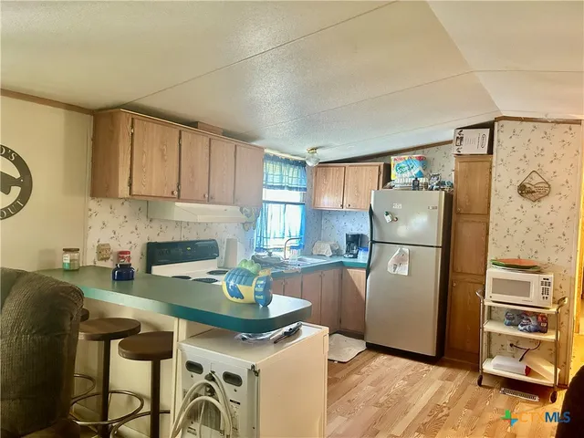 a kitchen with stainless steel appliances granite countertop a refrigerator a stove a sink and a counter space