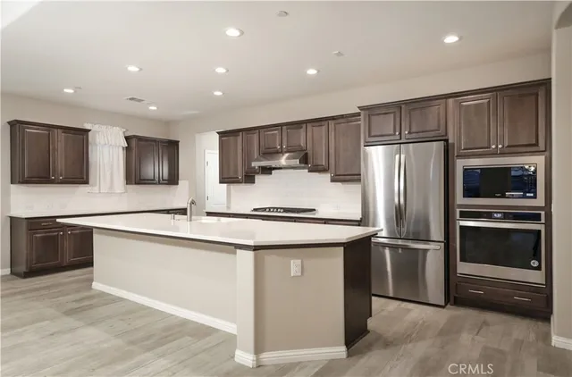 a kitchen with stainless steel appliances granite countertop a refrigerator a stove a sink and a microwave