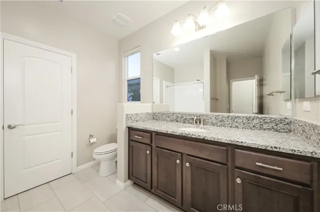 a bathroom with a granite countertop sink a toilet and a mirror