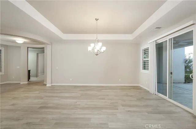 a view of an empty room with wooden floor and a ceiling fan