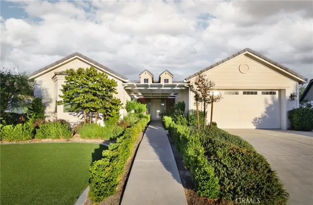 a view of a house with a small yard plants and a large tree
