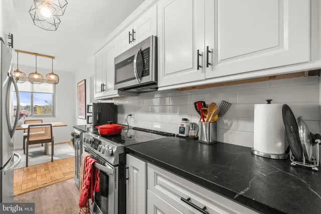 a kitchen with stainless steel appliances granite countertop a sink a stove and a wooden cabinets