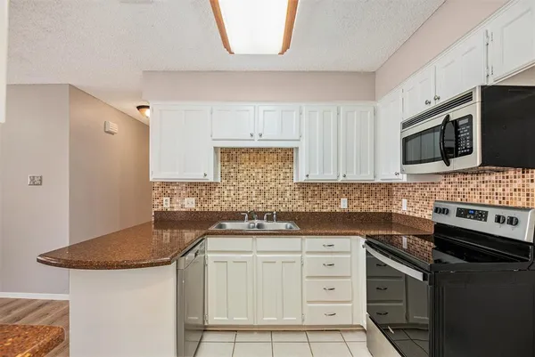 a kitchen with granite countertop a sink stove and microwave