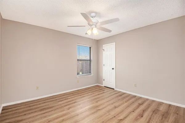 an empty room with wooden floor fan and windows