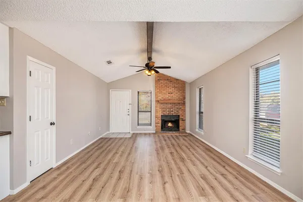 a view of empty room with wooden floor and fireplace