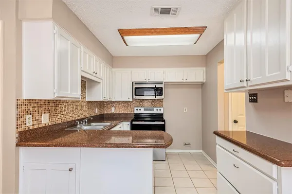 a kitchen with stainless steel appliances granite countertop a sink stove oven and white cabinets