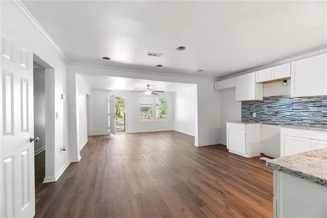 a view of an empty room with window and wooden floor