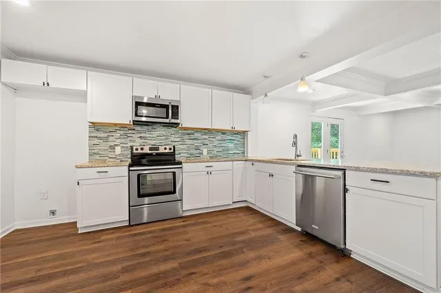 a kitchen with granite countertop white cabinets and stainless steel appliances