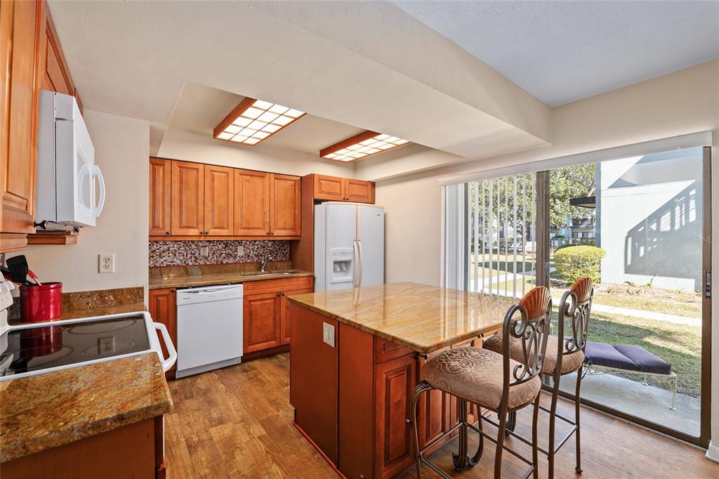 401 Northwest 39th Road, Unit 401C Gainesville, FL 32607 - Photo 11 of 62 a kitchen with stainless steel appliances granite countertop a stove top oven a sink dishwasher and a dining table with wooden floor