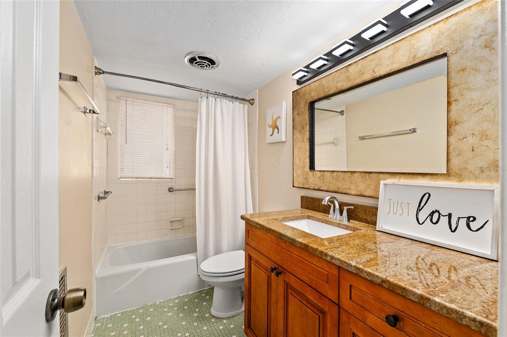 401 Northwest 39th Road, Unit 401C Gainesville, FL 32607 - Photo 20 of 62 a bathroom with a granite countertop sink a mirror a vanity and a bathtub