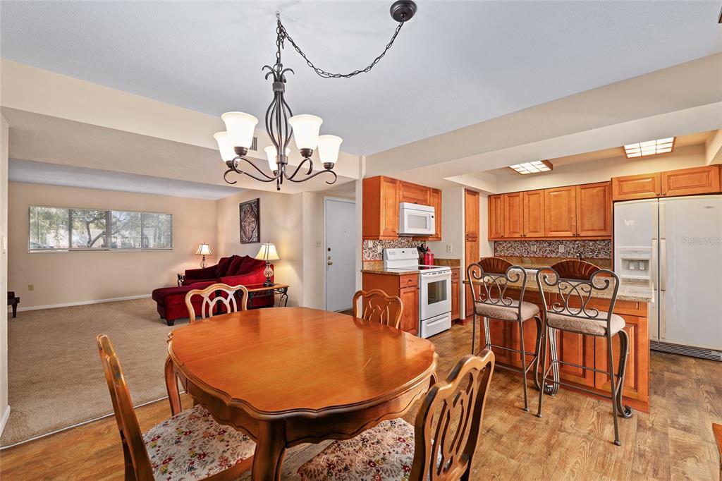 401 Northwest 39th Road, Unit 401C Gainesville, FL 32607 - Photo 10 of 62 a view of a dining room with furniture a chandelier and wooden floor