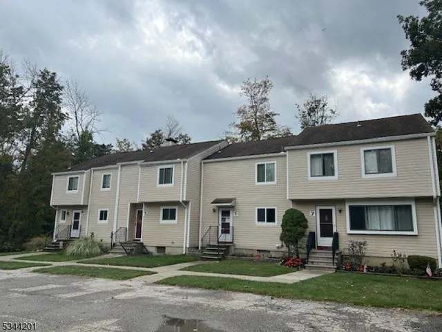 a view of a white house next to a yard with big trees and plants