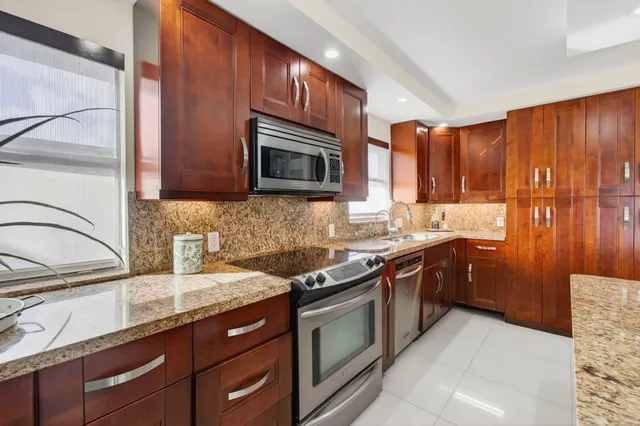 a kitchen with stainless steel appliances granite countertop a sink stove microwave and refrigerator