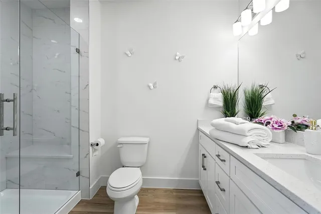 a bathroom with a granite countertop sink a toilet and shower