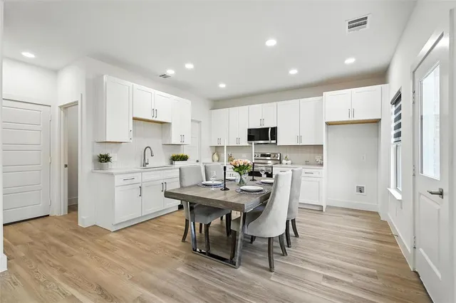 a kitchen with a table chairs refrigerator and microwave