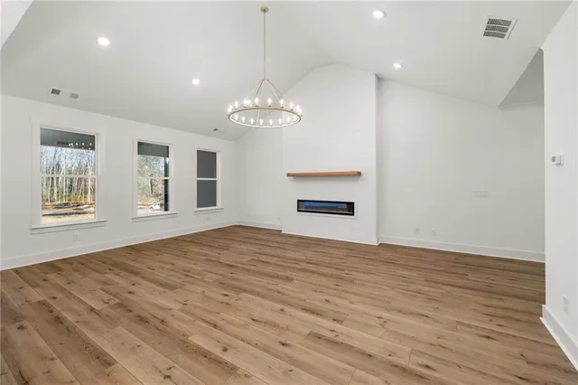 a view of empty room with wooden floor and kitchen view