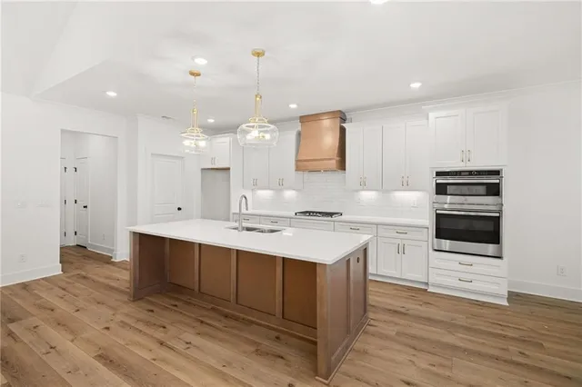 a room with kitchen island a sink stainless steel appliances and cabinets