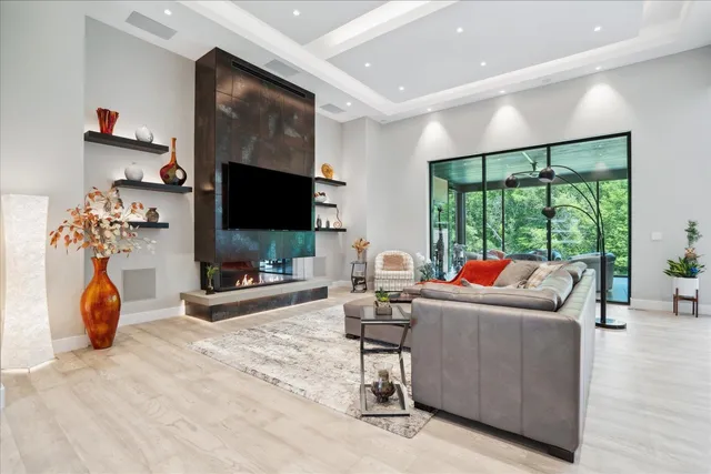 a living room with furniture a flat screen tv and a floor to ceiling window