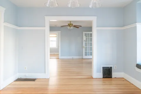 a view of a room with wooden floor and a ceiling fan