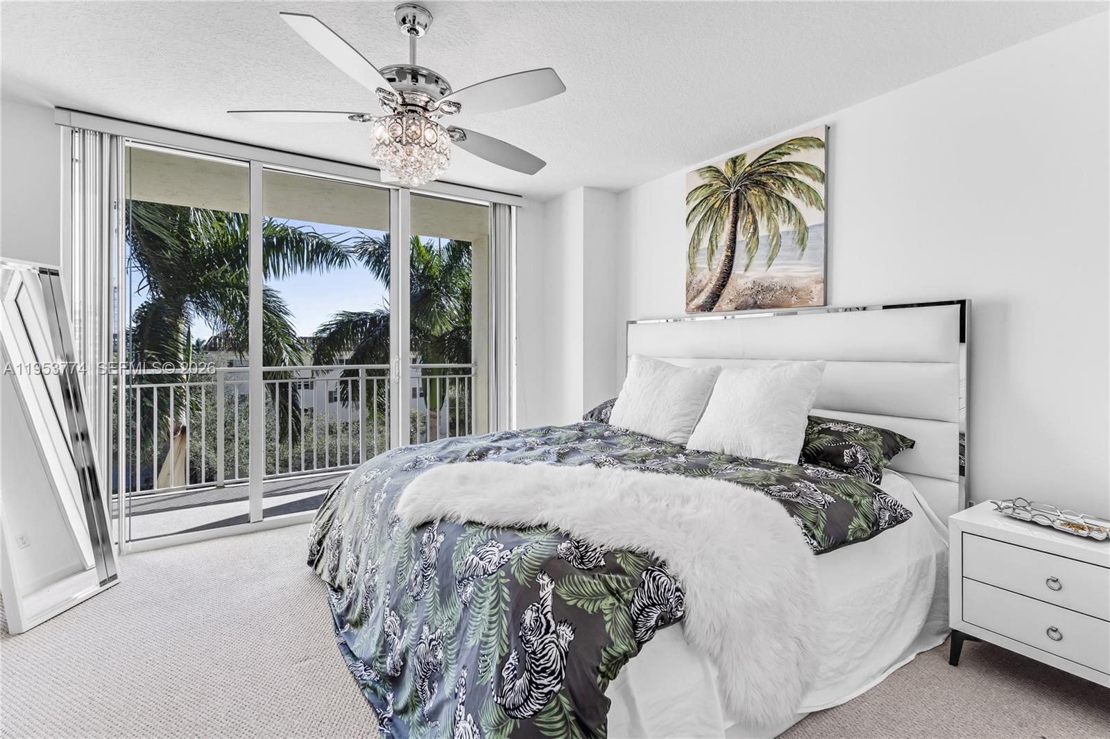 99 Southeast Mizner Boulevard, Unit 409 Boca Raton, FL 33432 - Photo 9 of 26 a bedroom with a bed a chandelier and a large window