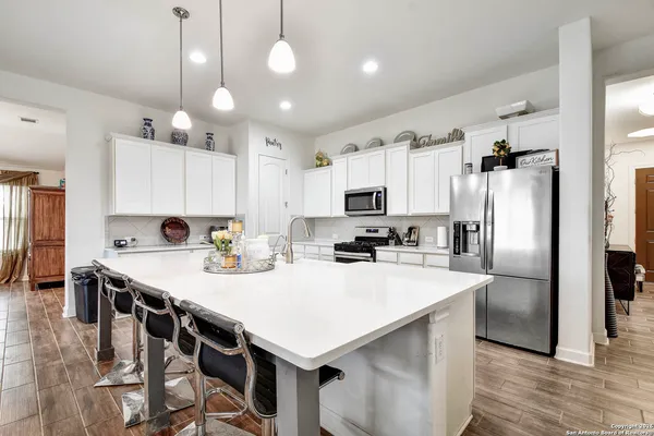 a kitchen with stainless steel appliances a table chairs refrigerator and microwave