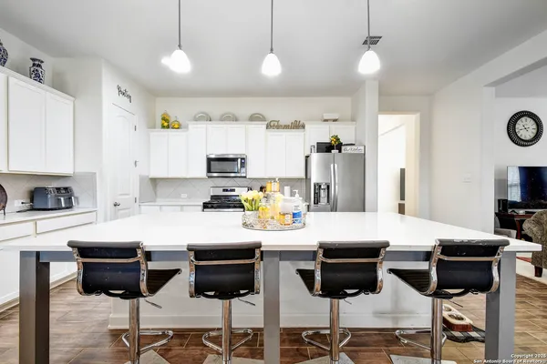 a kitchen with stainless steel appliances a dining table chairs and stove top oven