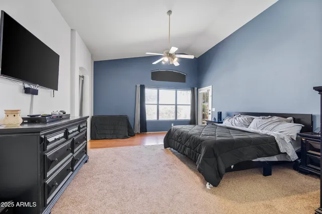 a spacious bedroom with a large bed chandelier and a window