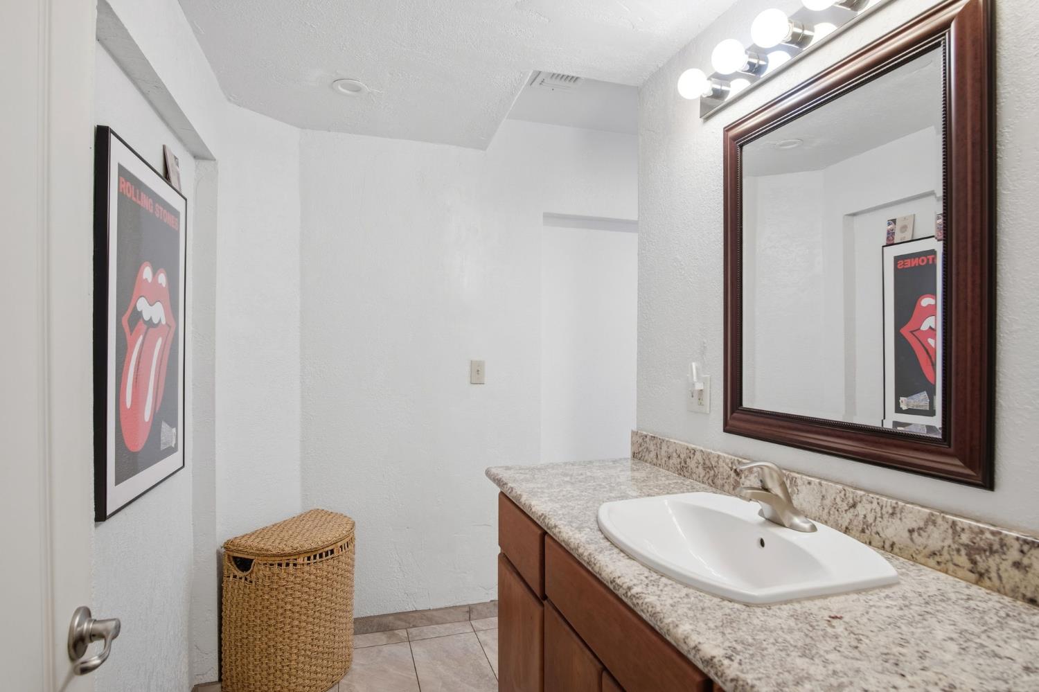 1740 Colorado Avenue Turlock, CA 95382 - Photo 22 of 37 a bathroom with a granite countertop sink a mirror and a