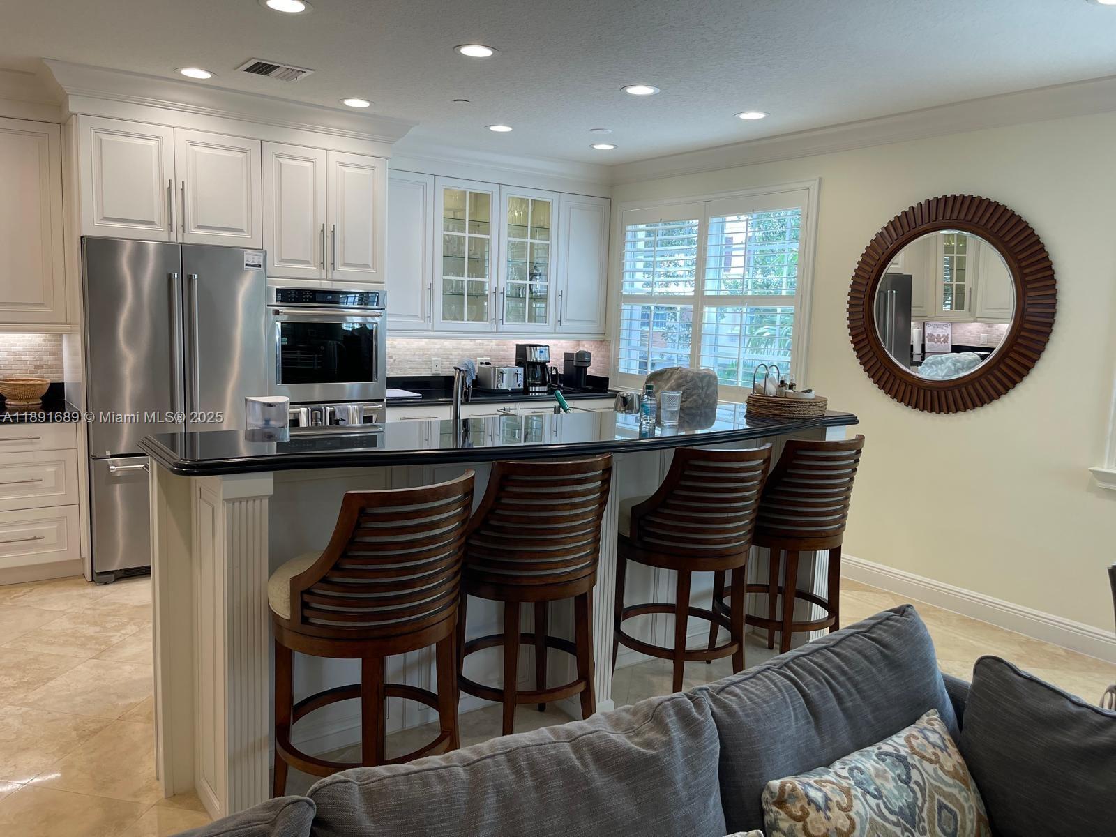 5565 Northeast Trieste Way Boca Raton, FL 33487 - Photo 11 of 30 a kitchen with a dining table chairs and a refrigerator
