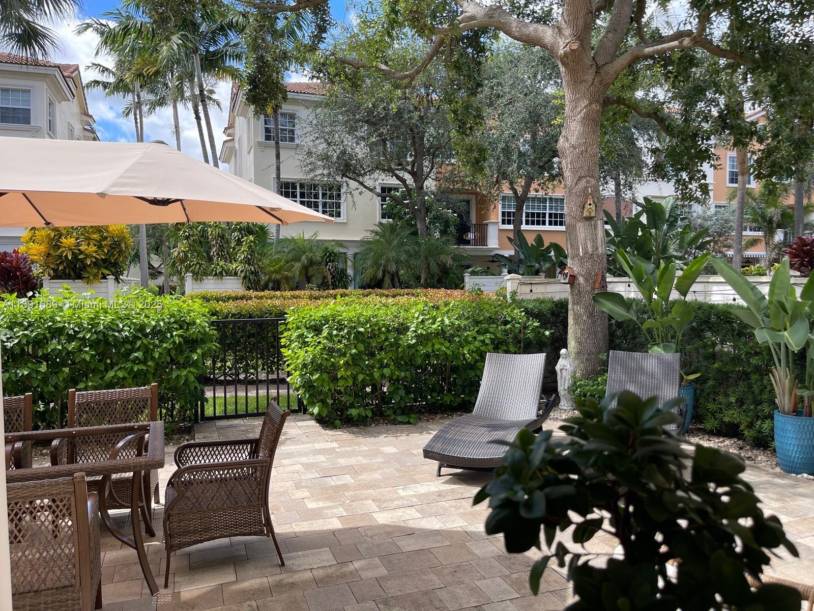 5565 Northeast Trieste Way Boca Raton, FL 33487 - Photo 25 of 30 a view of a patio with table and chairs potted plants and a palm tree