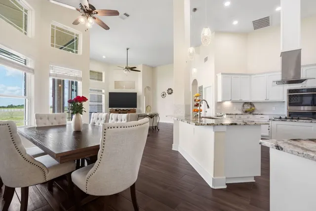 a kitchen with stainless steel appliances granite countertop a stove a refrigerator a kitchen island a dining table and chairs