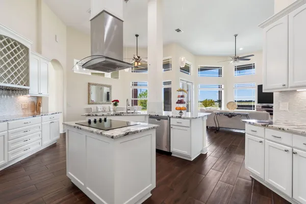 a kitchen with stainless steel appliances kitchen island granite countertop a sink cabinets and wooden floor