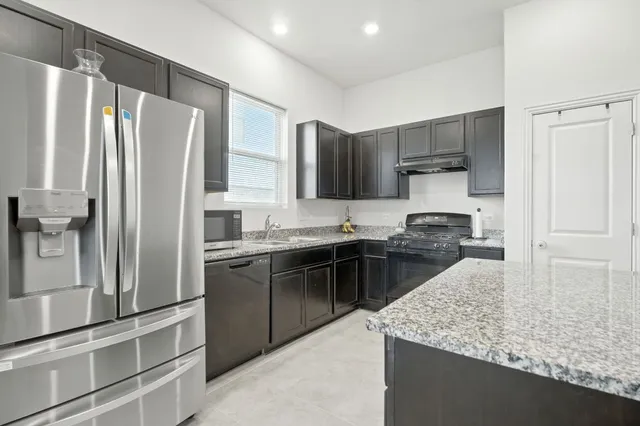 a kitchen with stainless steel appliances granite countertop a sink refrigerator and cabinets
