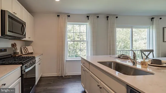 a kitchen that has a sink wooden floor and a stove top oven