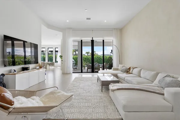 a living room with furniture large windows and wooden floor