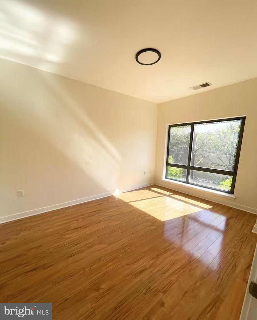 8005 13th Street, Unit 310 Silver Spring, MD 20910 - Photo 9 of 11 a view of an empty room with wooden floor and a window