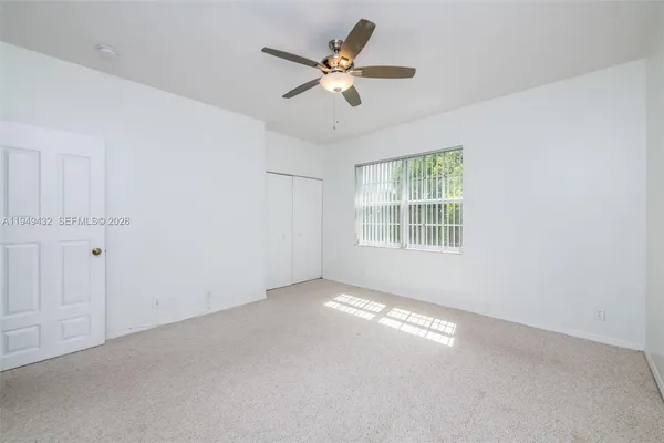 an empty room with windows and fan