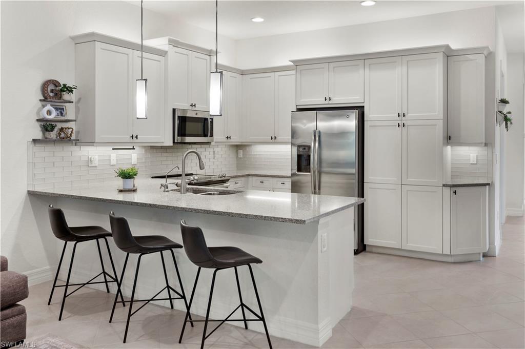 a kitchen with stainless steel appliances granite countertop a sink a stove a refrigerator and island with wooden floor