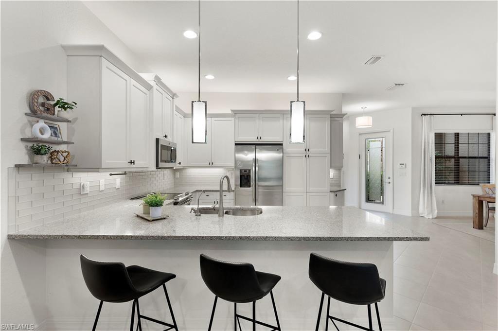 11989 Five Waters Circle Fort Myers, FL 33913 - Photo 11 of 32 a kitchen with refrigerator and chairs