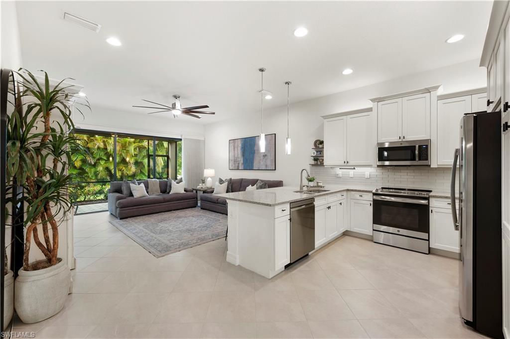 11989 Five Waters Circle Fort Myers, FL 33913 - Photo 12 of 32 a kitchen with stainless steel appliances kitchen island granite countertop a refrigerator oven a sink dishwasher and white cabinets with wooden floor