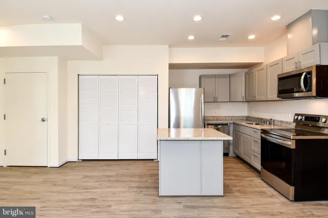 a kitchen with stainless steel appliances granite countertop a stove top oven a sink and a refrigerator