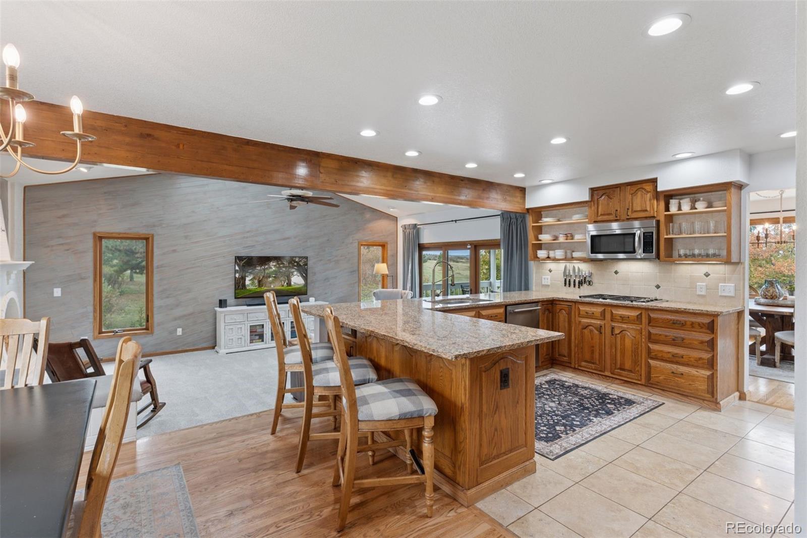 7501 Stroh Road Parker, CO 80134 - Photo 8 of 49 a kitchen with stainless steel appliances kitchen island granite countertop a table chairs sink and cabinets