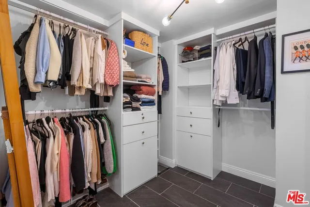 a view of walk in closet with clothes and shoes