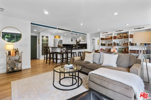 a living room with furniture kitchen view and a wooden floor
