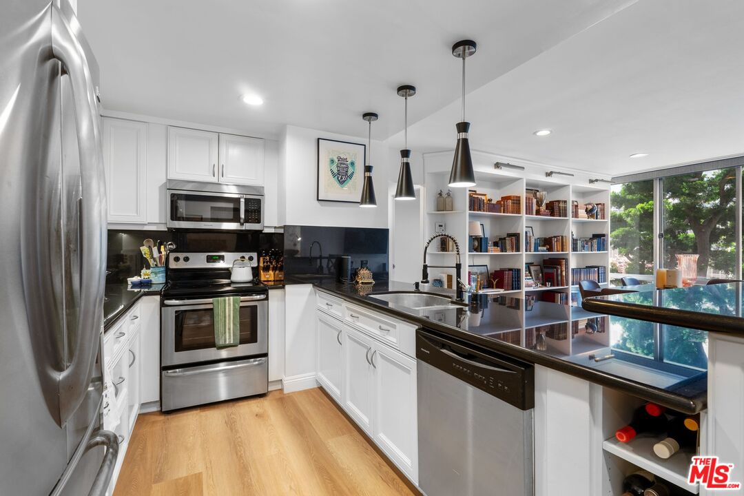 2160 Century Park East, Unit 211 Los Angeles, CA 90067 - Photo 7 of 24 a kitchen with stainless steel appliances a sink counter space and a window