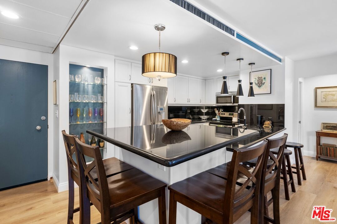 2160 Century Park East, Unit 211 Los Angeles, CA 90067 - Photo 9 of 24 a kitchen with stainless steel appliances kitchen island granite countertop a table chairs and a refrigerator