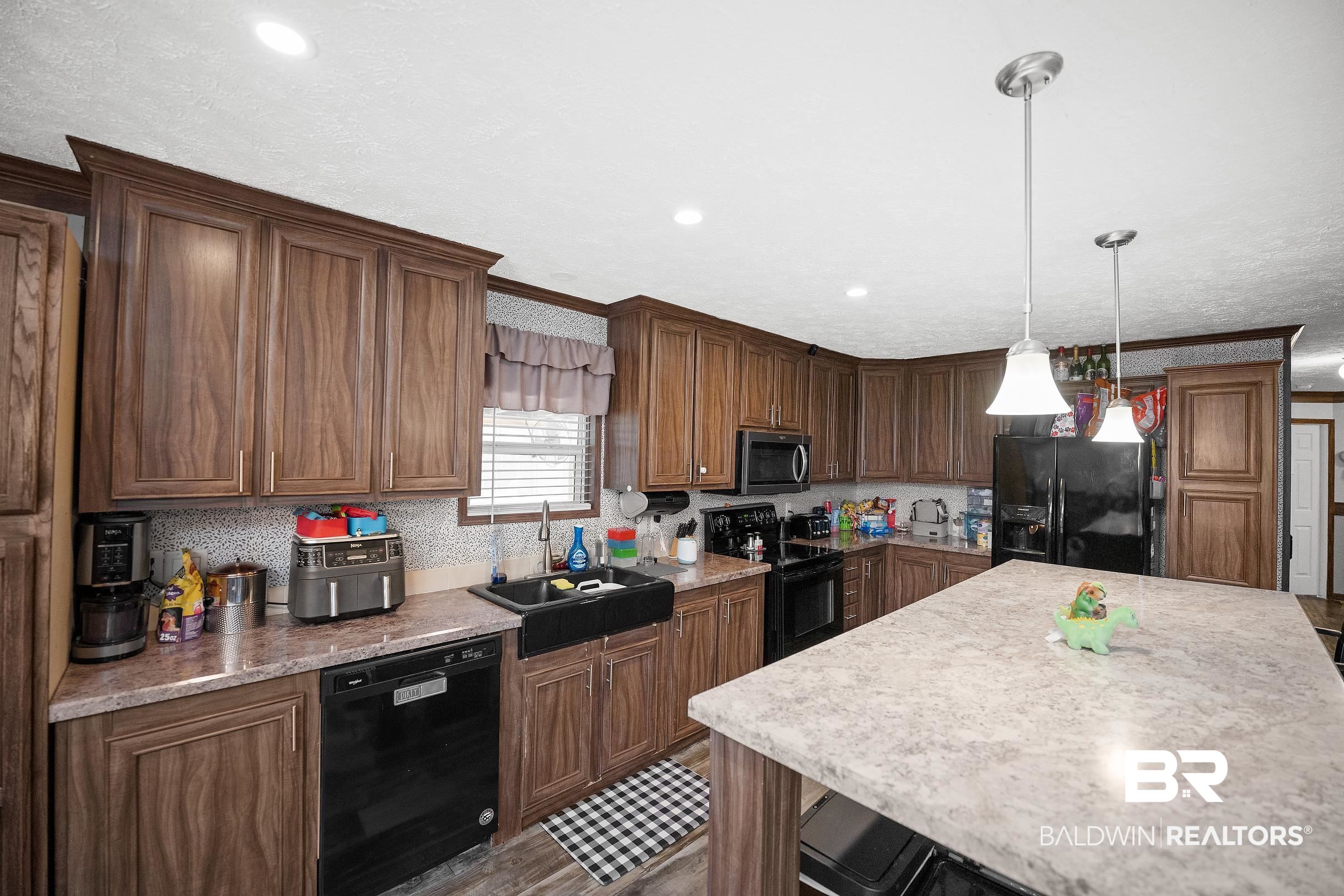 8630 Allison Lane Wilmer, AL 36587 - Photo 10 of 31 Kitchen with black appliances, hanging light fixtures, a kitchen island, recessed lighting, and light stone counters