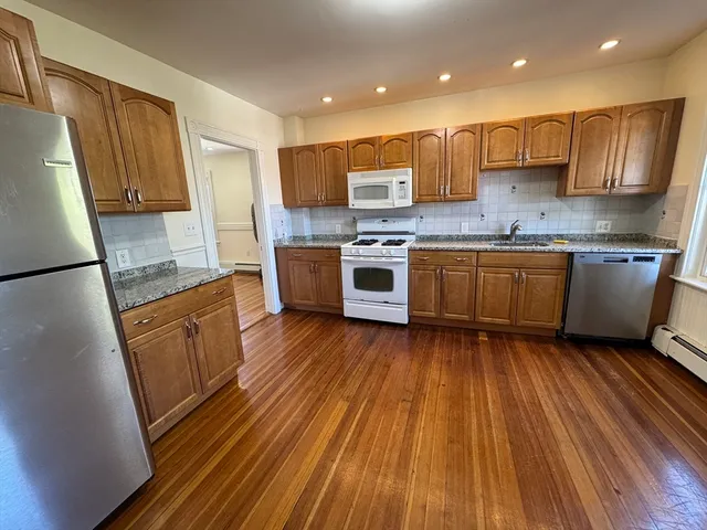 a kitchen with granite countertop wooden floors a stove and a refrigerator
